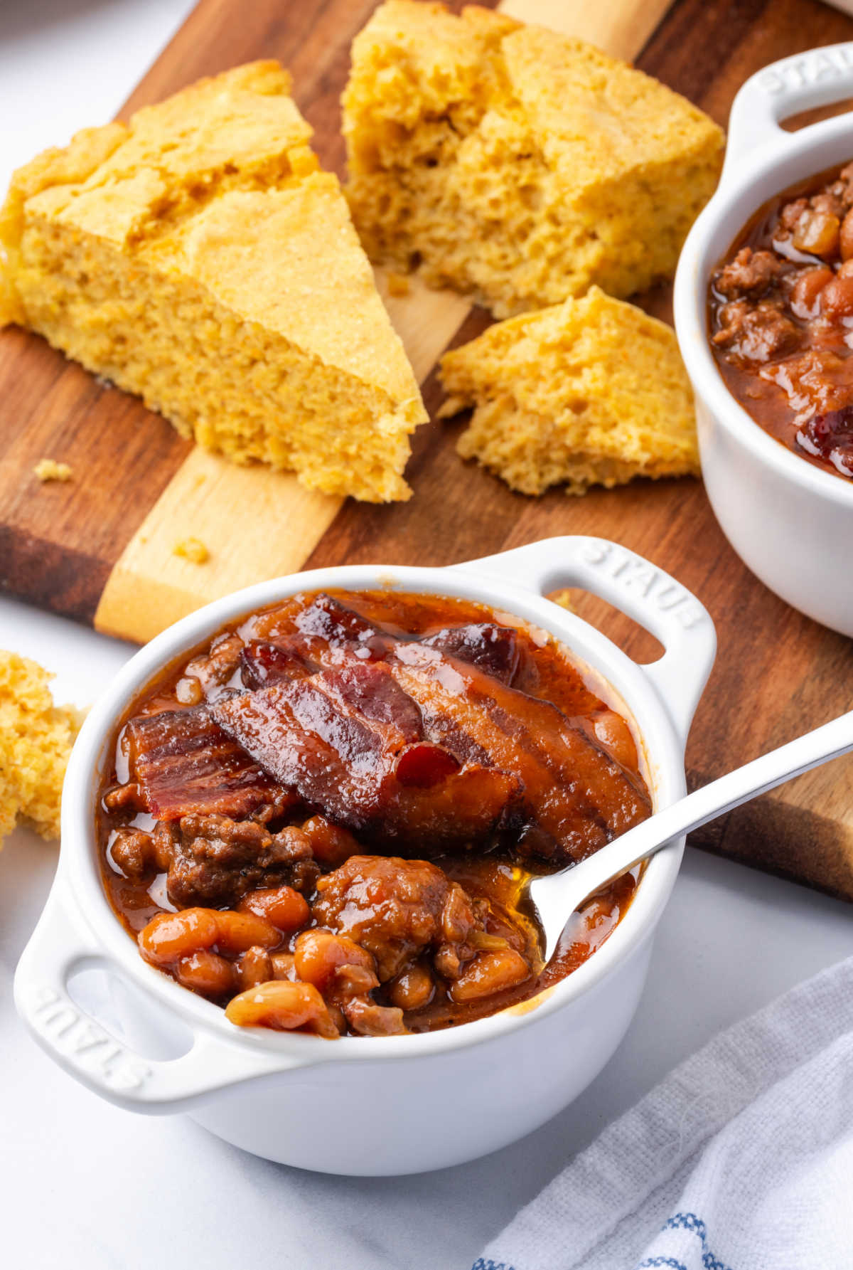 Baked beans with meat in small white crock.
