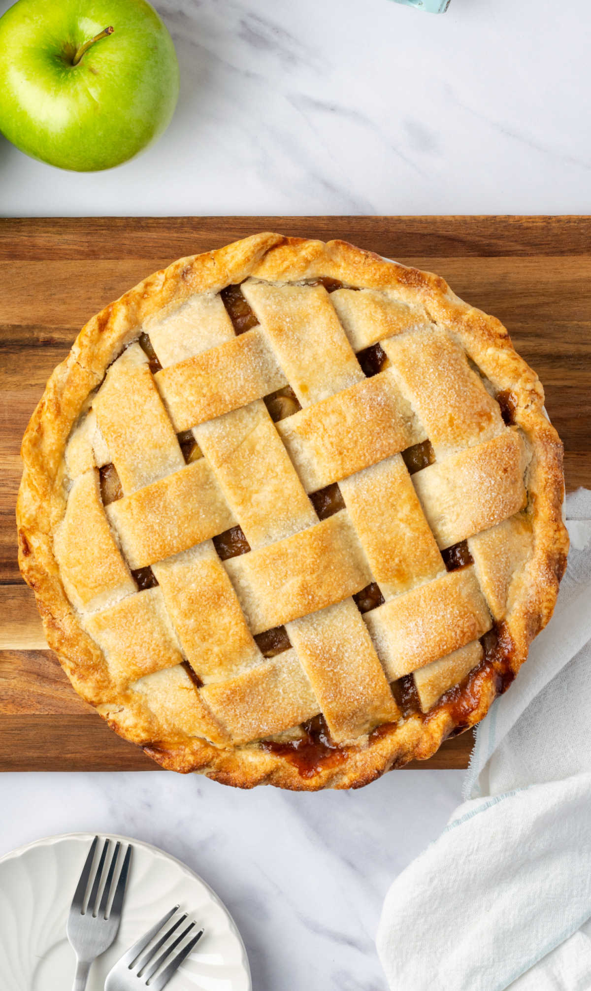 Apple pie with lattice crust on wooden cutting board.