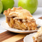 Slice of apple pie on small white plate.