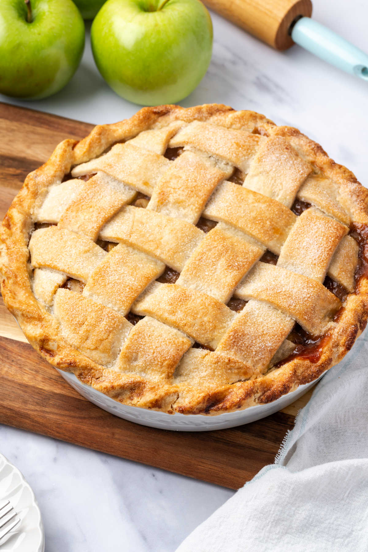 Pie with lattice crust, green apples in background.