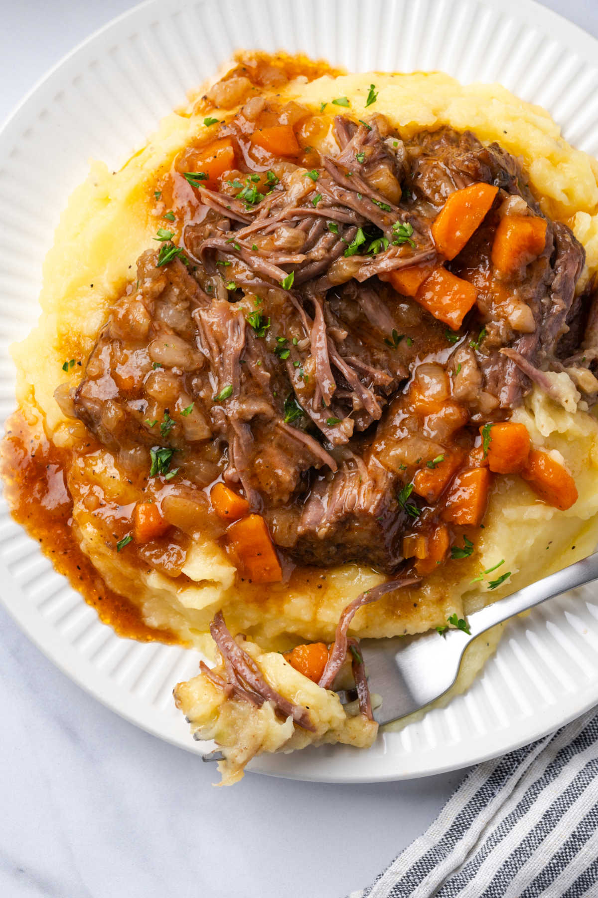 Plate with fork, short ribs, carrots and onions.