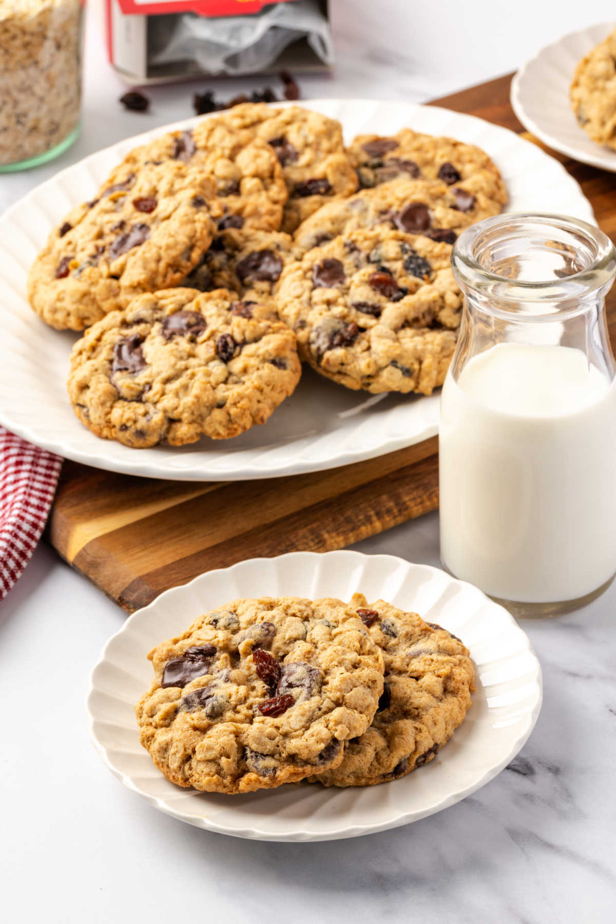 Oatmeal cookies on small white plate, jar of milk to side.