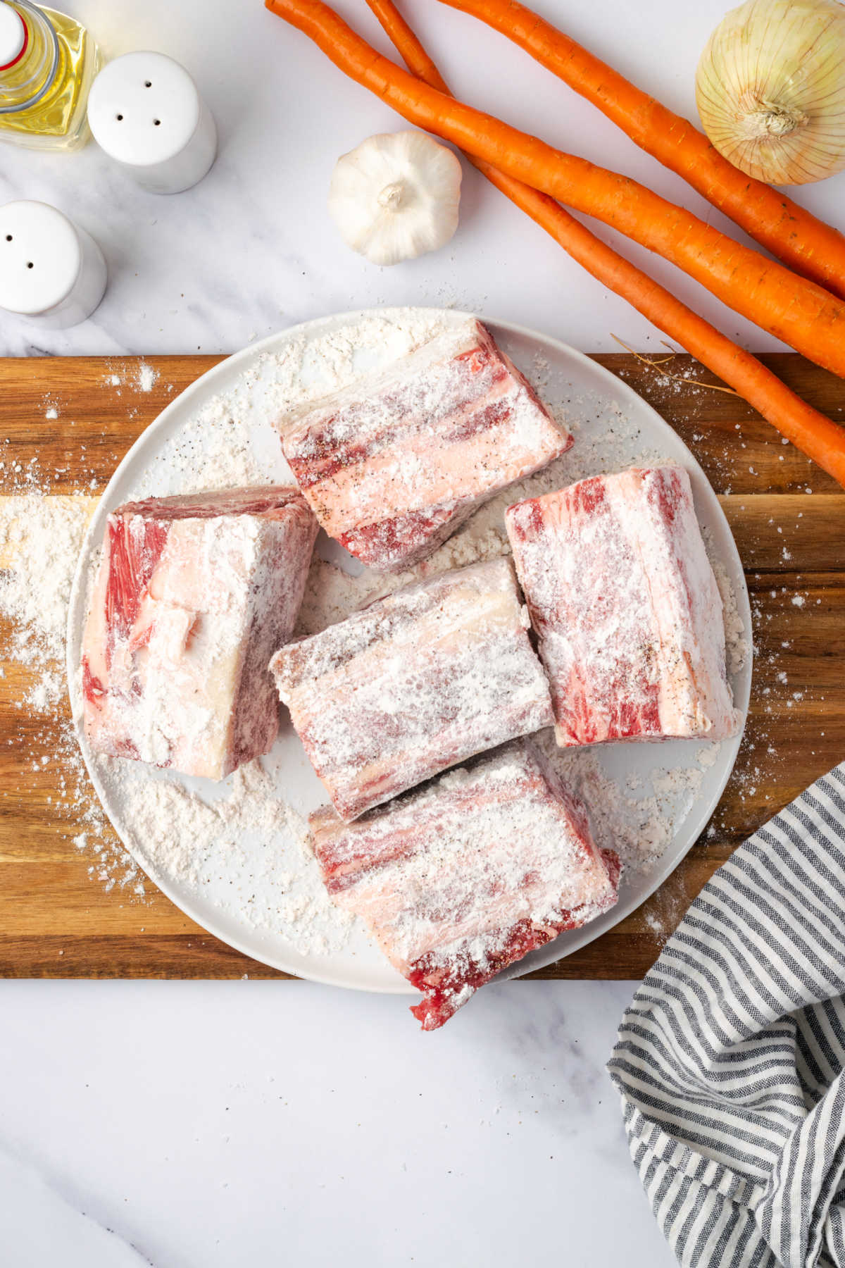 Step images seasoning short ribs with flour, salt and pepper on small white plate.