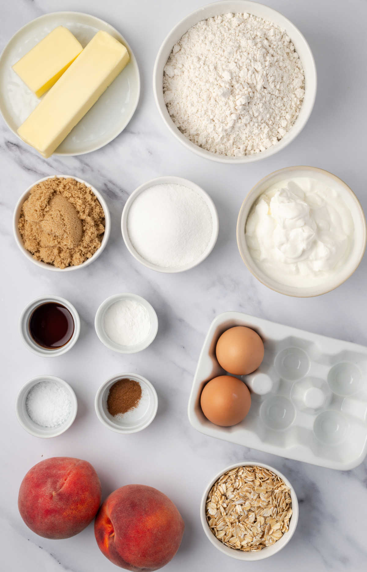 Ingredients for muffins in small white bowls, fresh peaches.