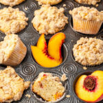 Close up of peach muffins with fresh peaches in muffin tin.