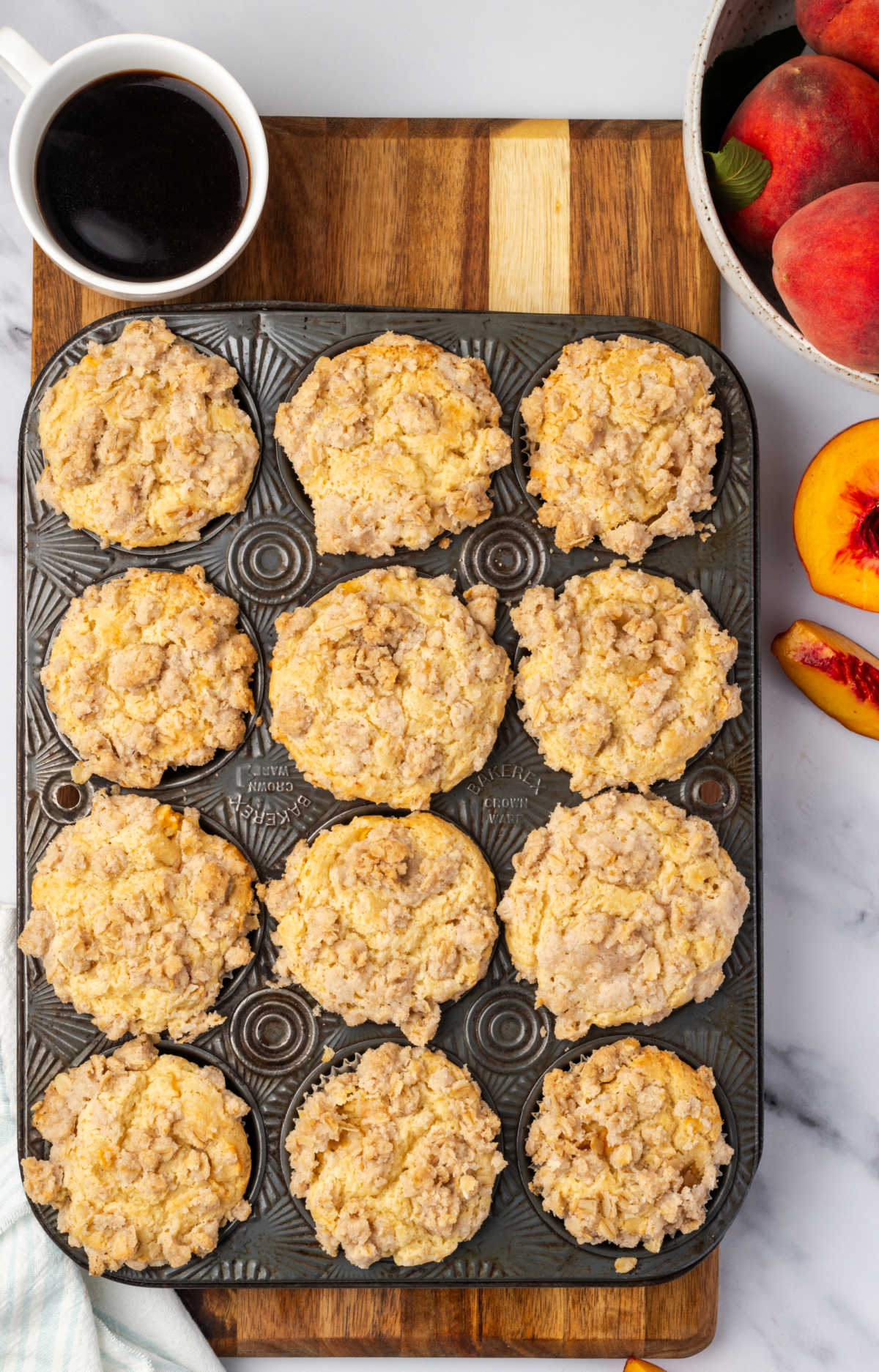 Baked muffins in vintage muffin pan, fresh peaches around.