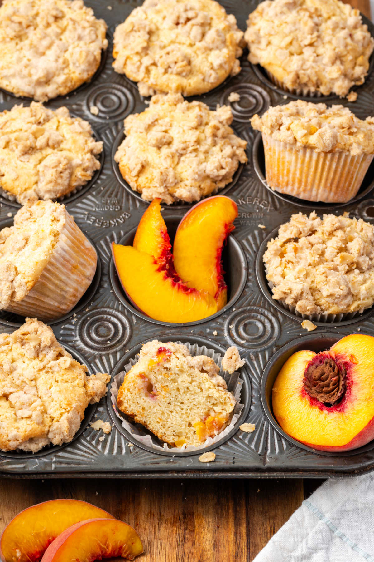 Muffins in vintage muffin pan, fresh peach slices in pan.