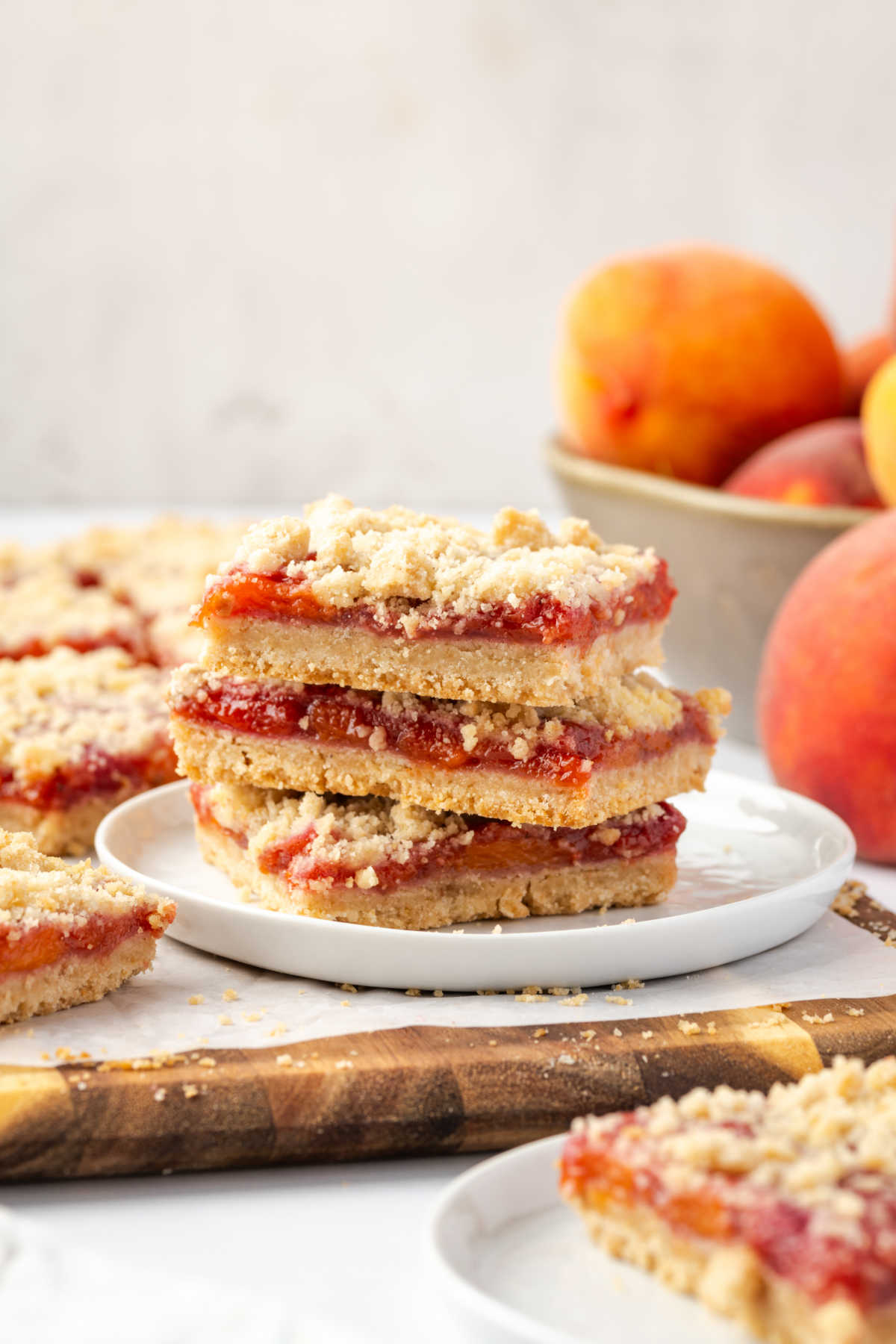 Peach bars stacked on each other, fresh peaches in background.