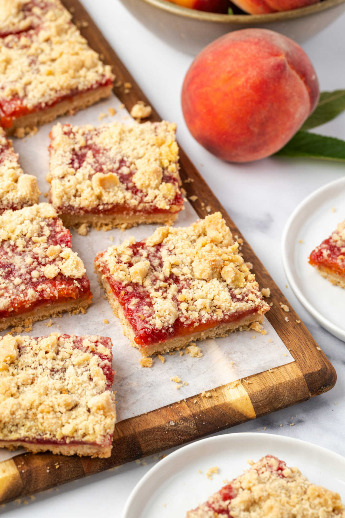 Close up of peach bars cut into squares on wood cutting board.