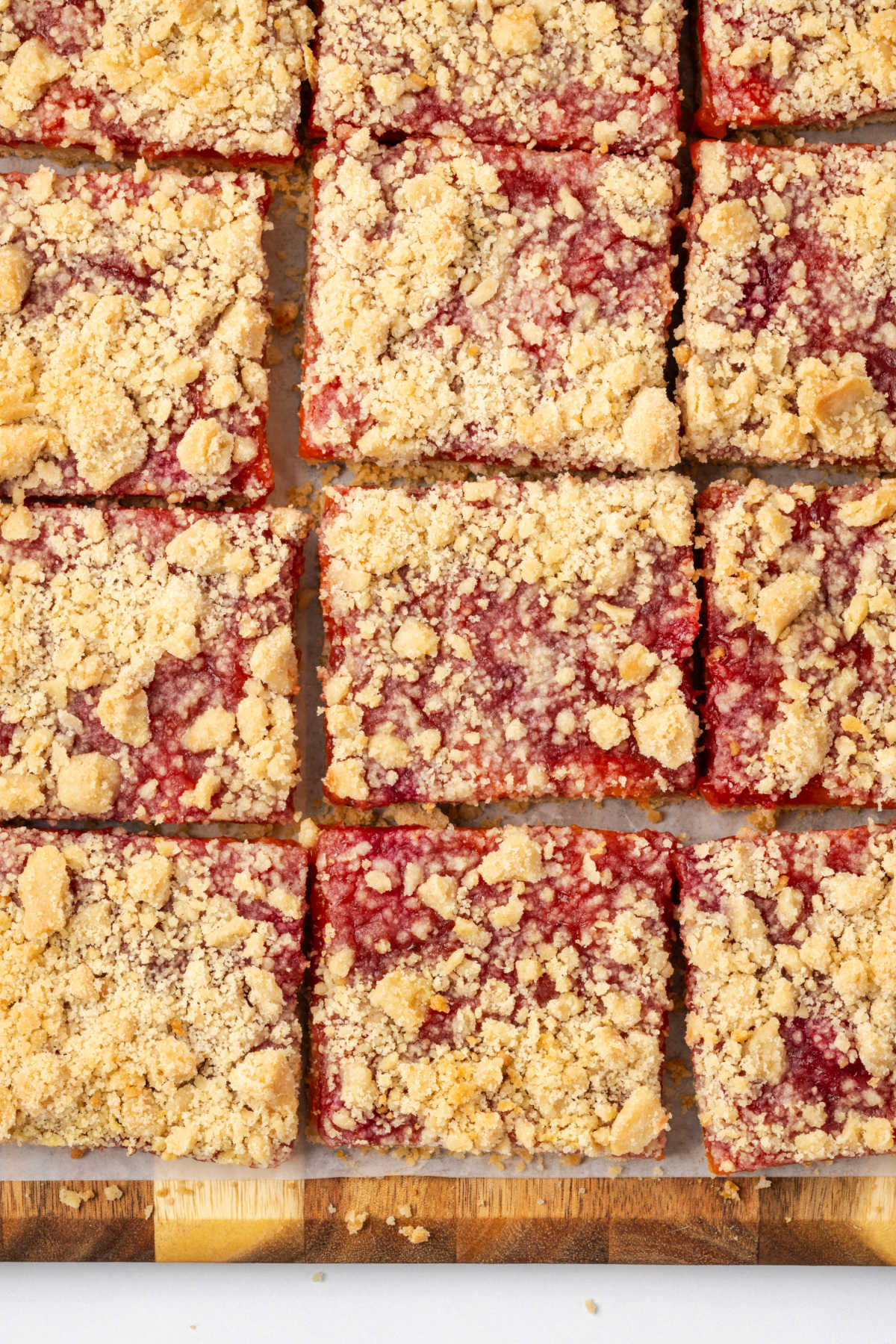 Peach crumb bars cut into squares on wood cutting board.