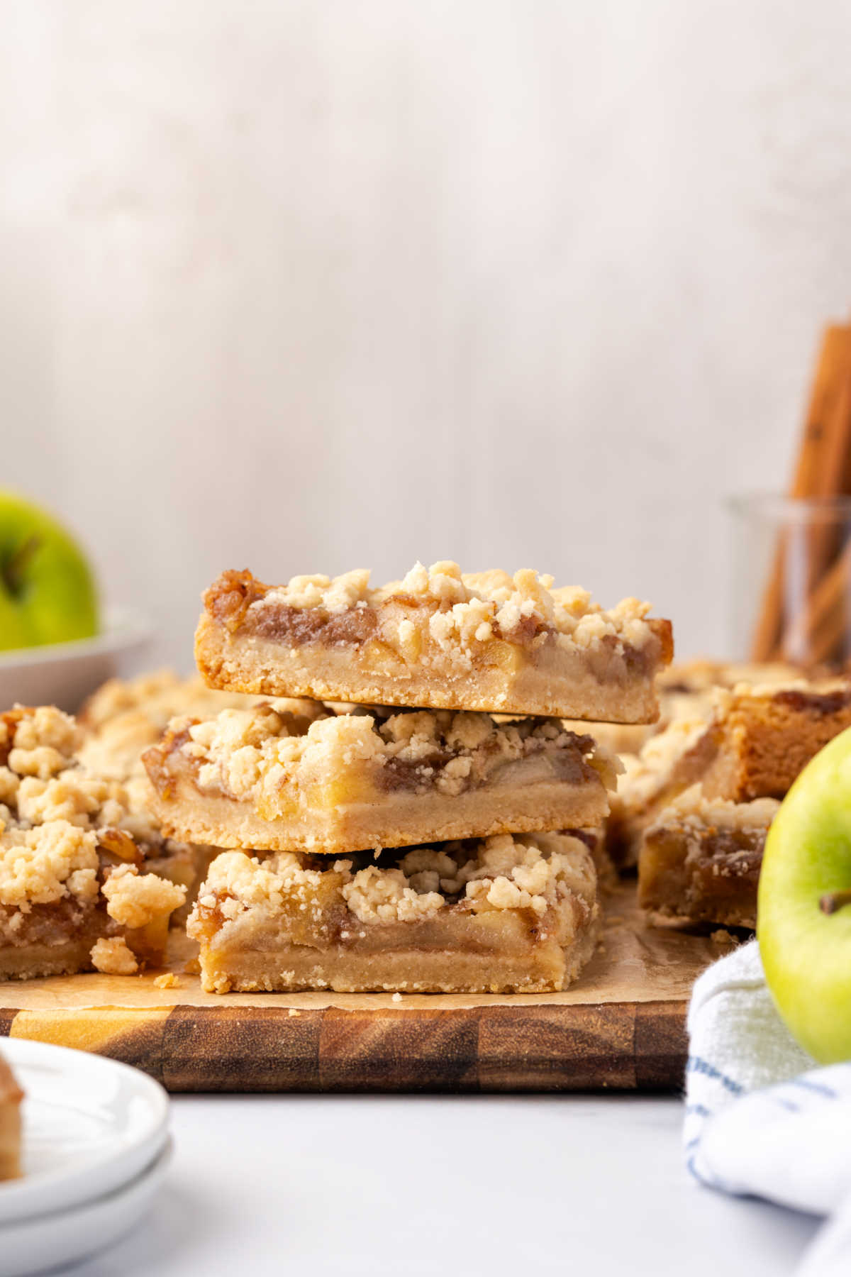 Stacked apple crumb bars on wood cutting board.