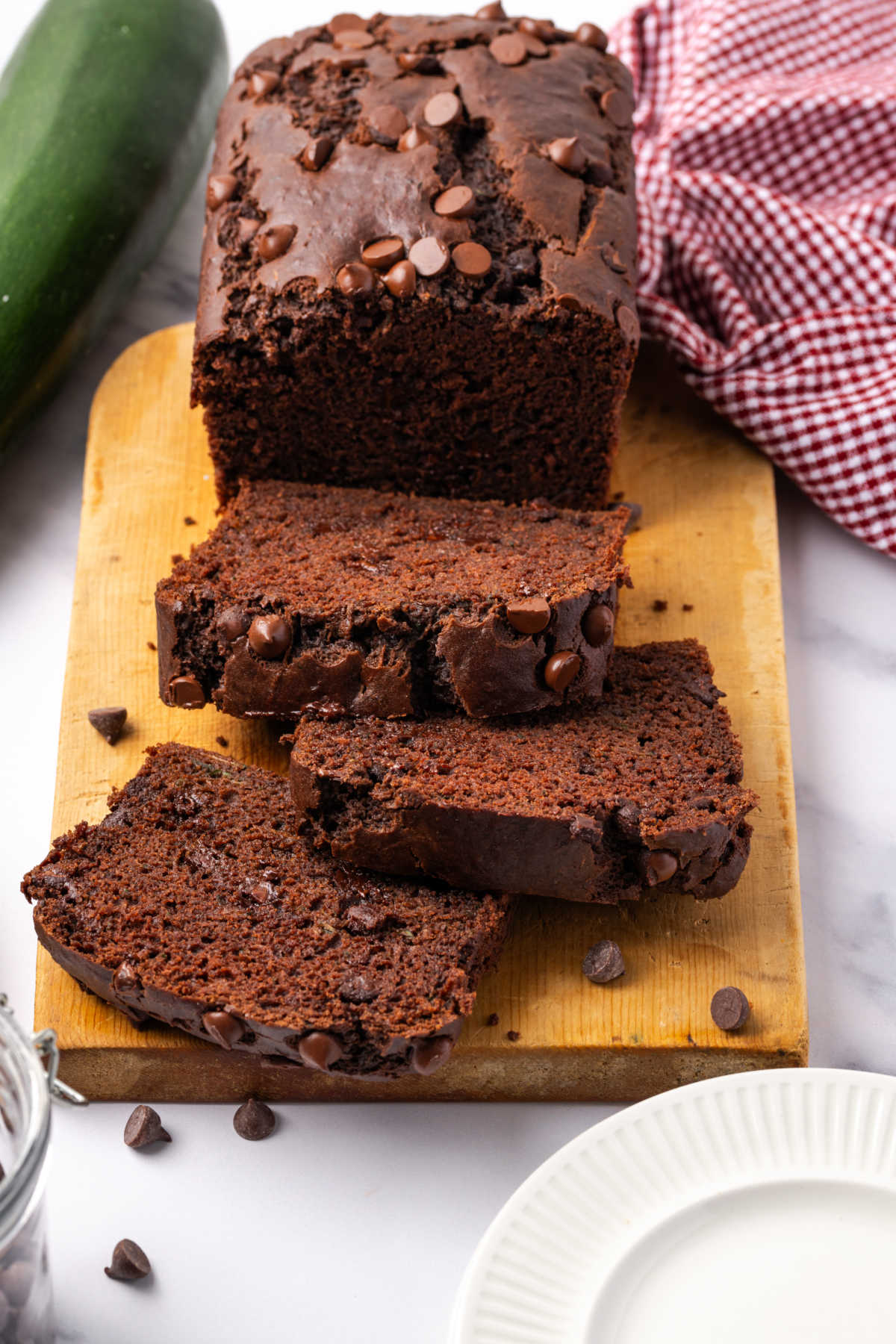 Chocolate zucchini bread partially sliced on wood cutting board.
