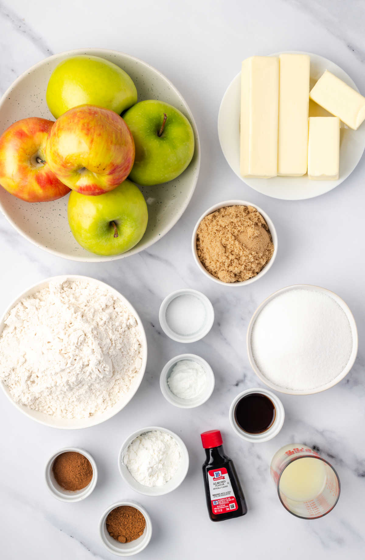 Ingredients in small white bowls, apples in bowl for crumb bars.