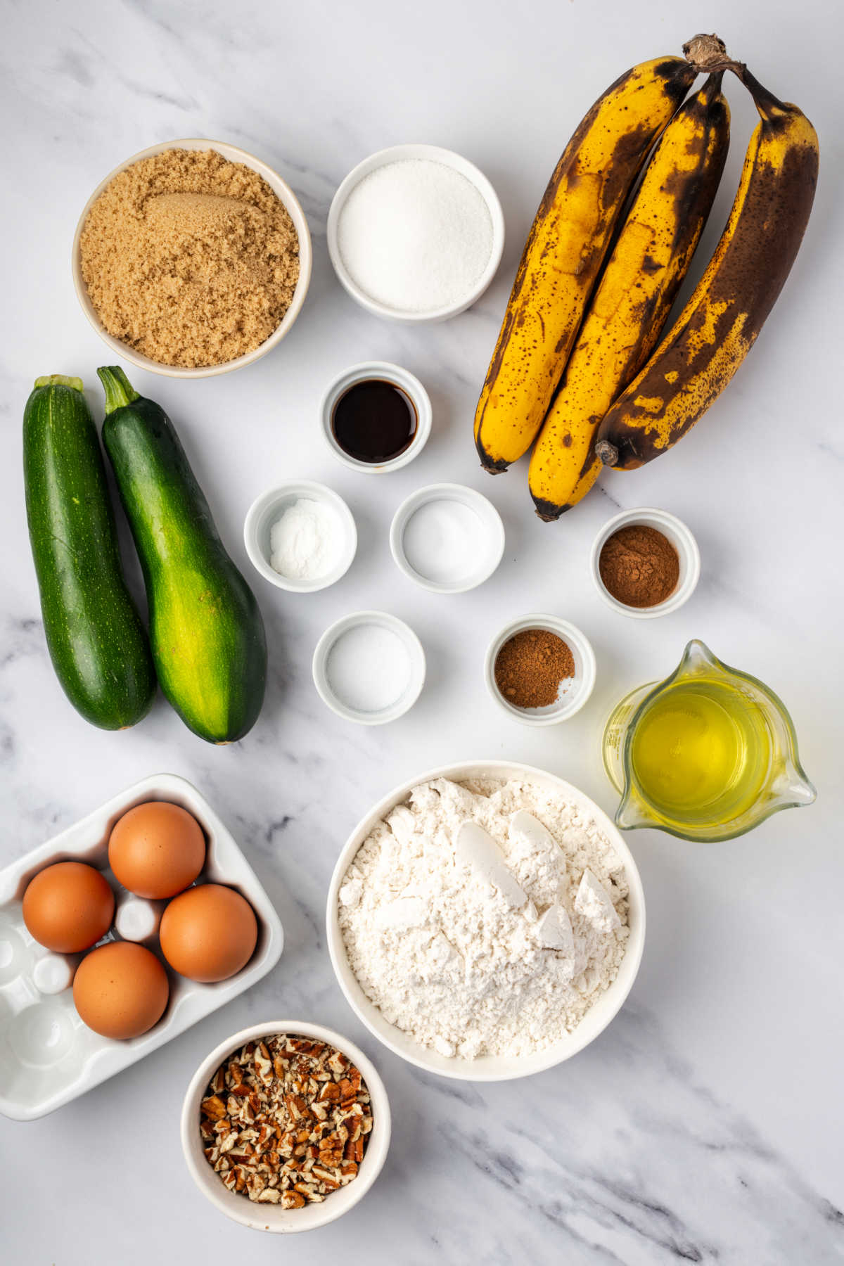 Ingredients in small white bowls for zucchini bread.