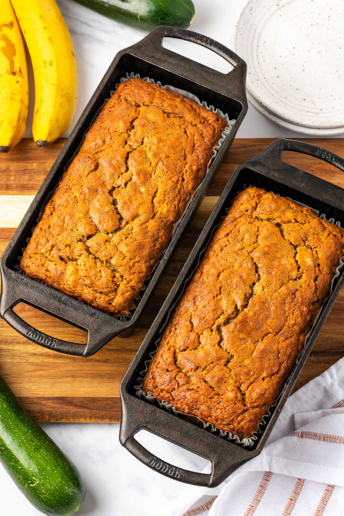 Zucchini bread baked in cast iron loaf pans on wood cutting board.