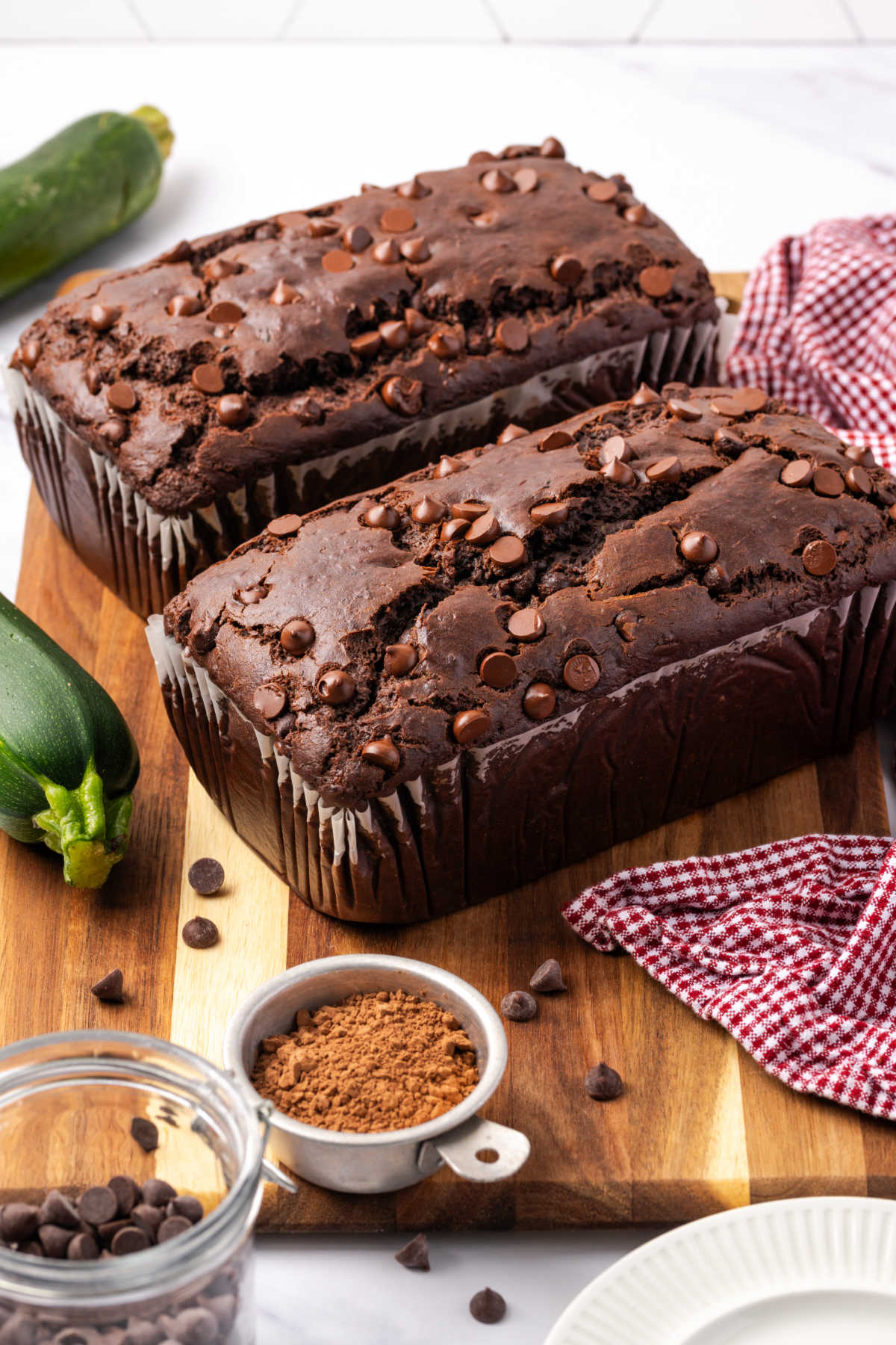 Two loaves of chocolate bread on wooden cutting board.