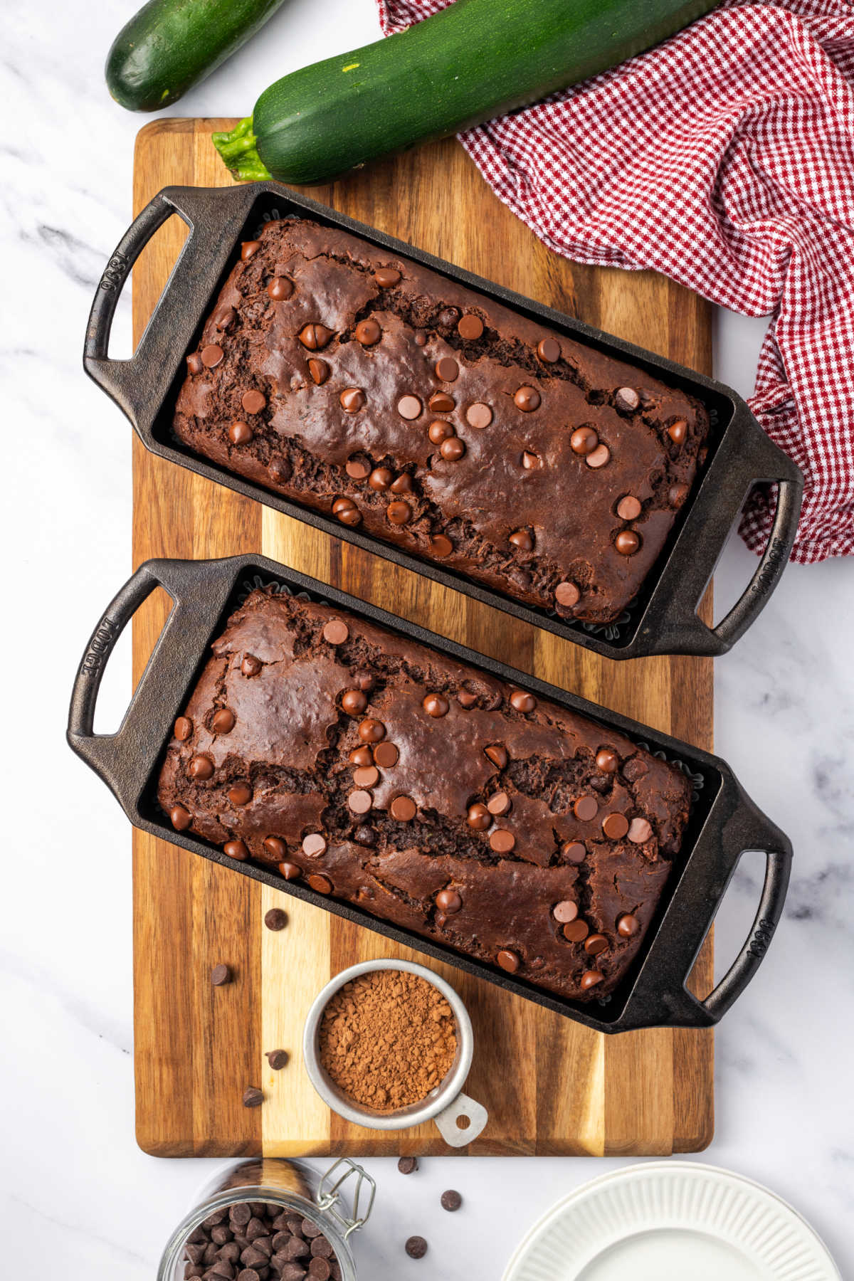 Chocolate loaf cakes in cast iron loaf pans on wood cutting board.