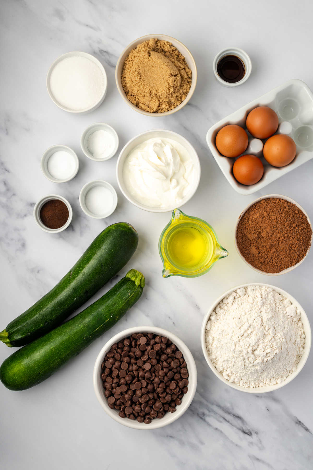 Ingredients in small white bowls for chocolate zucchini bread.