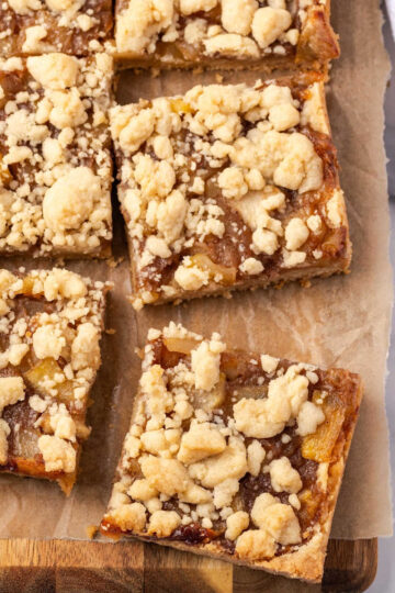 Apple bars cut into squares on wood cutting board.