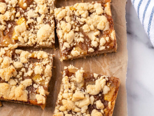 Apple bars cut into squares on wood cutting board.