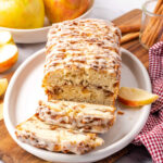 Apple fritter loaf partially sliced on white oval dish.