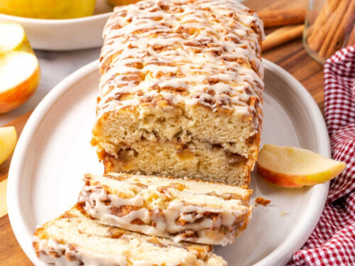 Apple fritter loaf partially sliced on white oval dish.