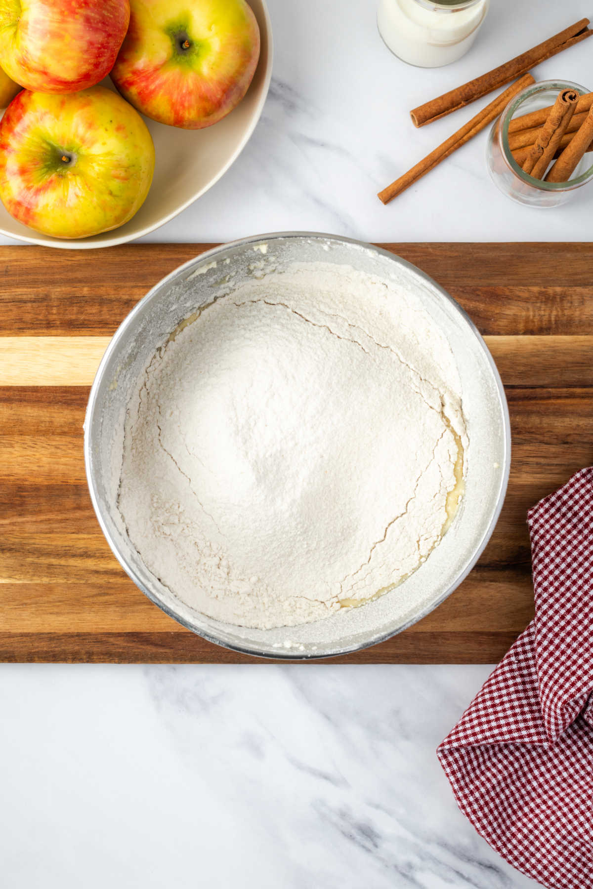 Adding flour to cake batter in metal mixing bowl.