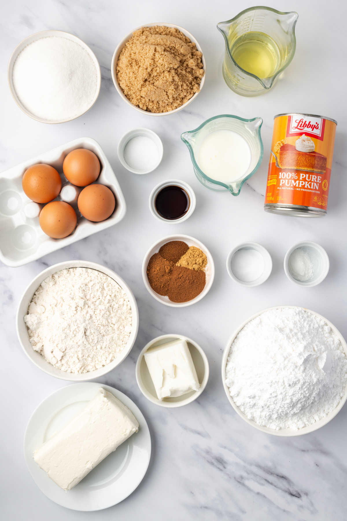 Ingredients in small white bowls, can of pumpkin for pumpkin cake.